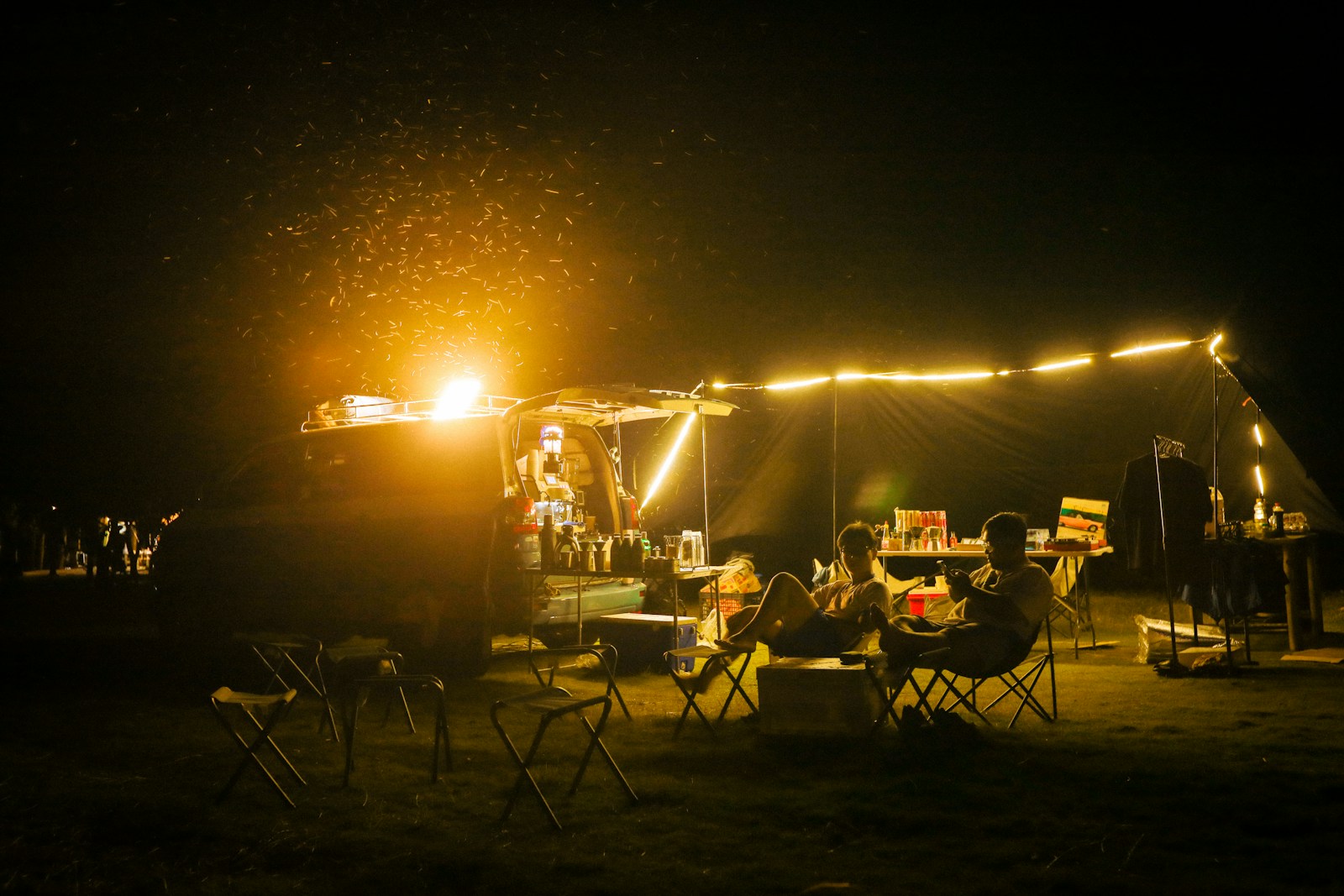 People enjoying a campfire at a campsite at night.